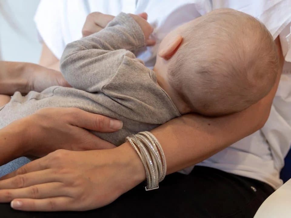 Trattamento osteopatico delicato di un neonato in braccio alla mamma
